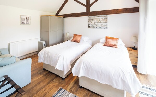 A bedroom with two single beds, a wardrobe, a radiator, and a wooden floor. - Deer Cottage at Rowden Manor - Sleeps 5 & Parking (Chippenham)