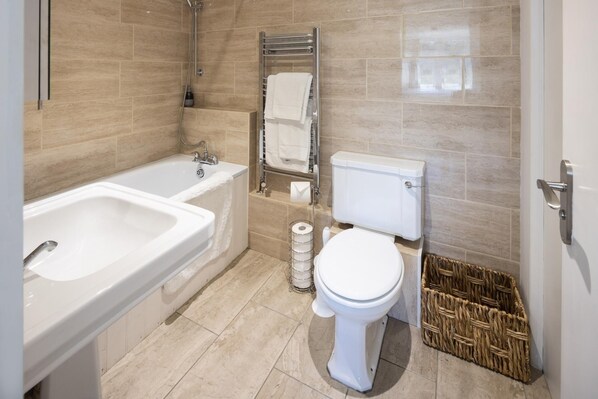 A bathroom with a bathtub, toilet, and a towel rack. - The Dovecote 3-bed Cottage, Rowden Manor (Chippenham)