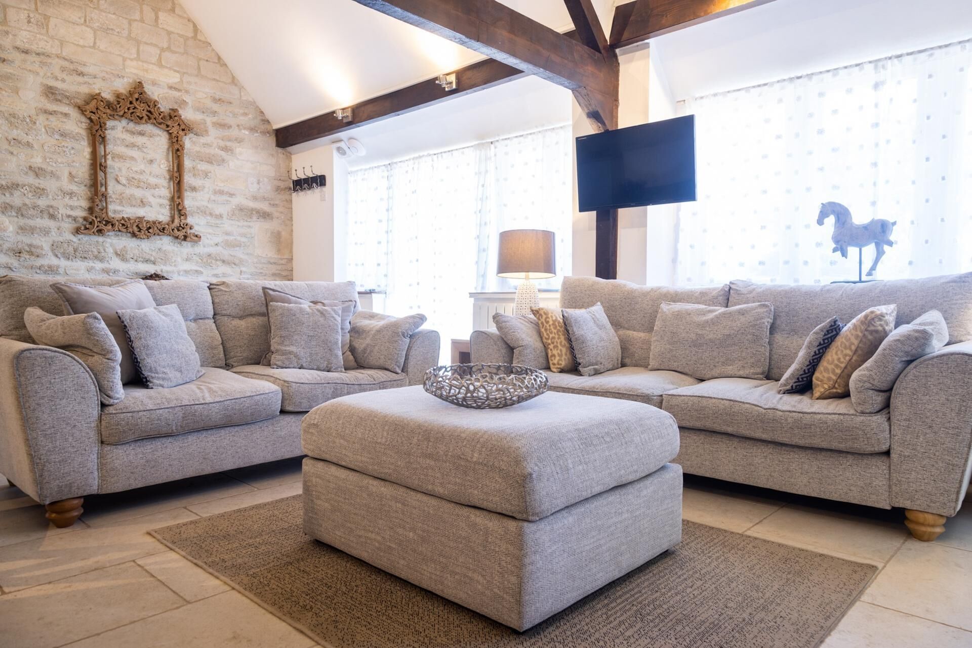 A living room with a sectional sofa, a coffee table, and a stone wall.
