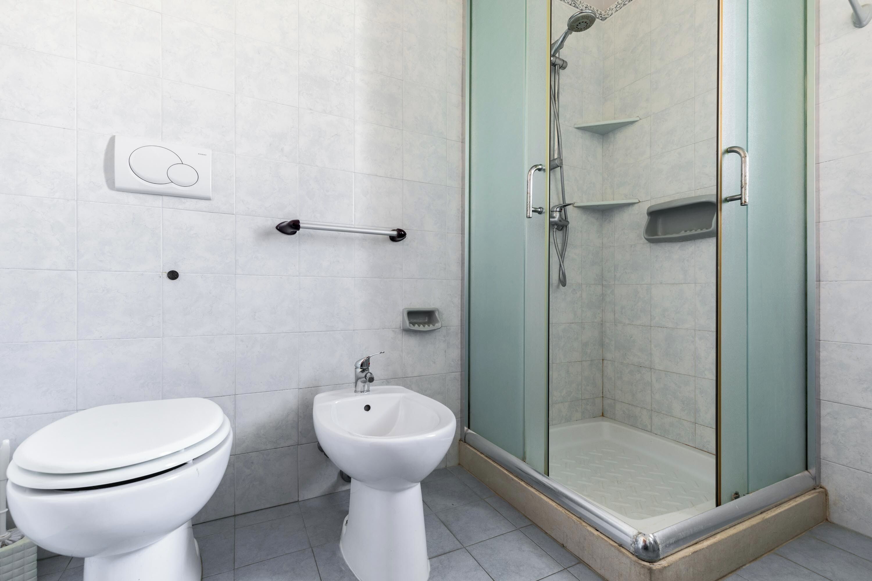 Un baño con inodoro, bidé y ducha con mampara de vidrio.