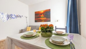 A dining area with a table set for two, a vase of orange flowers, and a painting on the wall. - I Sognatori - Bilo Plus by BarbarHouse (Torre Squillace)