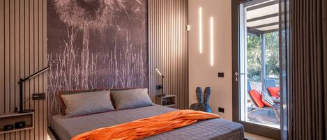 A modern bedroom with a large bed, a view of the outdoors, and a unique wall art piece.