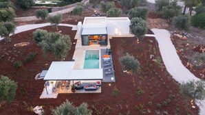 Een modern huis met een zwembad, terras en tuin.
