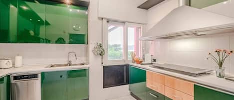 Una cucina moderna con mobili verdi, lavastoviglie e una finestra che illumina naturalmente l'ambiente.
