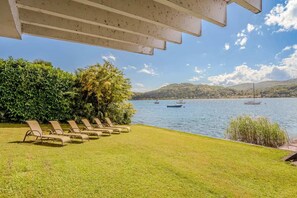 A poolside area with lounge chairs and a view of a lake with boats. - Italian Lakes Lakeside Villa With Direct Lake Access (Ranco)