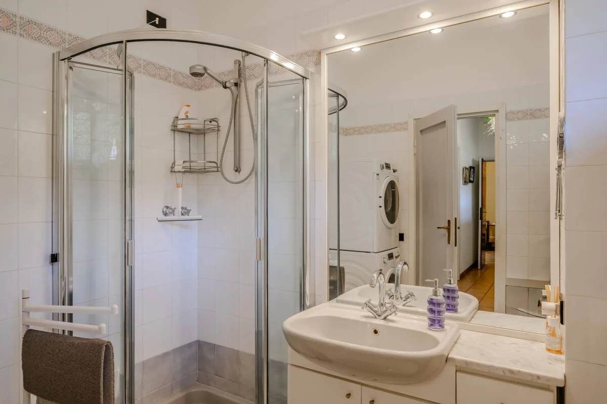 Un baño moderno con ducha envuelta en vidrio, un espejo grande y un lavabo con tocador.