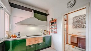 A modern kitchen with green cabinets, a stainless steel range hood, and a red shelf with kitchen items. - Italian Lakes Lakeside Villa With Direct Lake Access (Ranco)