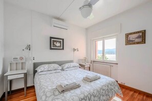 A bedroom with a bed, bedside table, and a window with a view. - Italian Lakes Lakeside Villa With Direct Lake Access (Ranco)