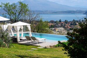 A pool area with a view of a lake and mountains, surrounded by greenery. - Family Friendly Italian Lakes Holiday Rental With Pool (Lesa)
