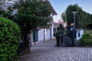 A paved pathway leading to a gated entrance with a small building and a security camera. - Family Friendly Italian Lakes Holiday Rental With Pool (Lesa)