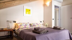 Une chambre à coucher avec un lit, des oreillers, une table de chevet, une lampe et un luminaire fixé au mur.