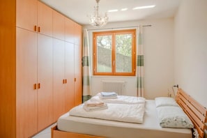 Ein Schlafzimmer mit einem Bett, einem Holzschrank und einem Fenster mit Vorhängen.