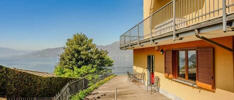 A balcony with a view of the sea, a wooden deck, and a building with a balcony.