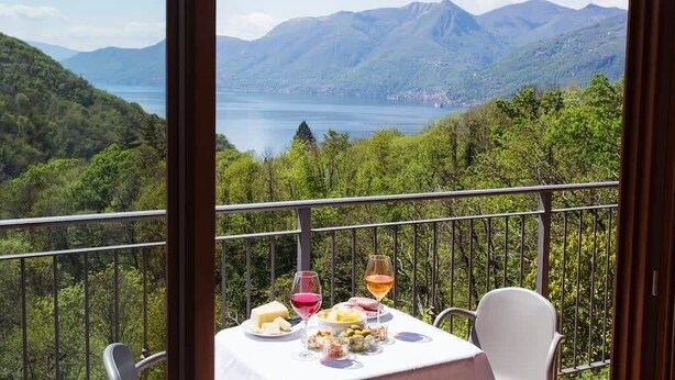 A table set with food and drinks on a balcony overlooking a mountainous landscape. - Dumenza Villas (Dumenza)