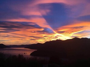 Ein Sonnenuntergang über einer Berglandschaft mit einem Gewässer.