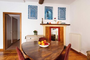 Ein Essbereich mit einem Holztisch, einer Obstschale und einem Kamin.