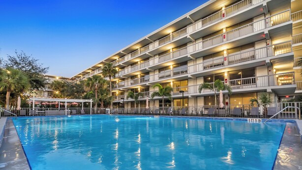 Un hotel con piscina, diversi balconi e aree salotto all'aperto.