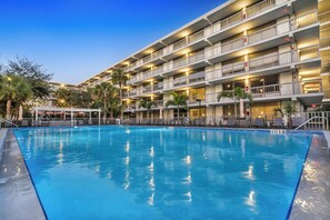 A hotel with a swimming pool, multiple balconies, and outdoor seating areas. - The Irlo (Kissimmee)