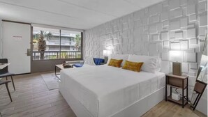 Camera d'albergo moderna con un letto grande, una scrivania e un balcone con vista sulla città.