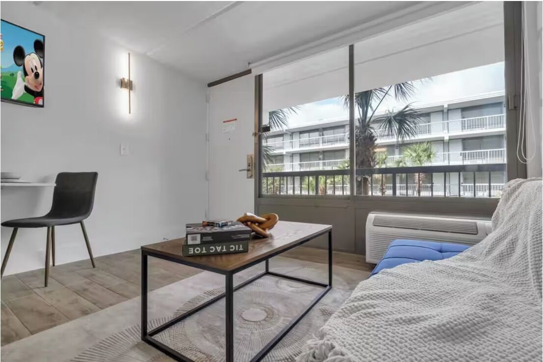 A modern room with a large window, a desk, a chair, and a bed.
