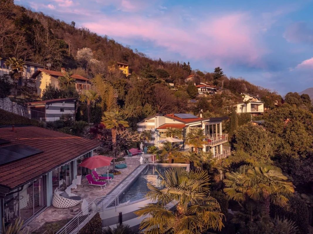 A hillside property with a swimming pool, outdoor seating, and multiple buildings.