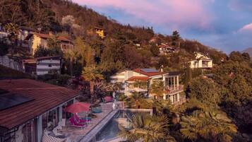A hillside property with a swimming pool, outdoor seating, and multiple buildings.
