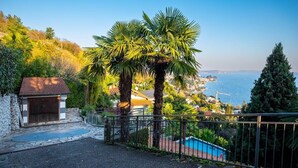 A residential property with a stone wall, a small garage, a metal gate, and a swimming pool. - Pallanza Villas (Verbania)