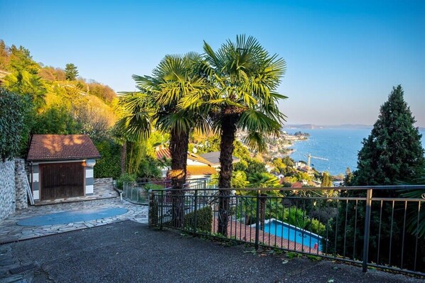 A residential property with a stone wall, a small garage, a metal gate, and a swimming pool.