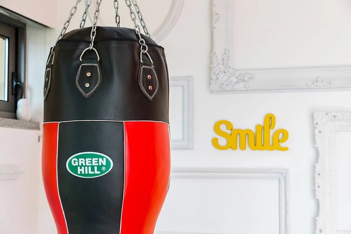 Un sac de frappe noir et rouge orné du logo « Green Hill », suspendu à une chaîne.