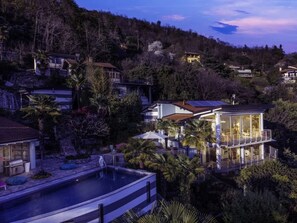 A residential area with a modern house featuring a swimming pool, surrounded by lush greenery and hills in the background. - Pallanza Villas (Verbania)