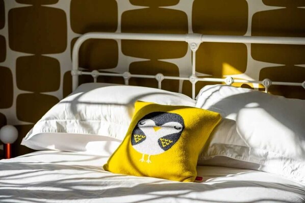 A bed with white bedding and a yellow pillow with a bird design. - Pallanza Villas (Verbania)