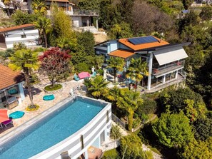 A modern house with a swimming pool, surrounded by lush greenery and a clear sky. - Pallanza Villas (Verbania)