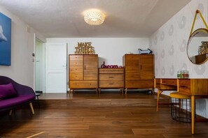 A room with a wooden dresser, a purple sofa, a wooden desk, and a chandelier. - Pallanza Villas (Verbania)