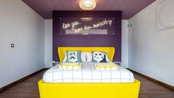 A bedroom with a bed, a neon sign, and a chandelier.