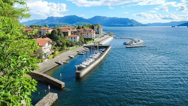 Ein Yachthafen am Wasser mit vertäuten Booten, einer anlegenden Mole und Gebäuden entlang der Küste.