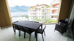 Ein Balkon mit Tisch und Stühlen, der auf ein Gewässer und Gebäude blickt.
