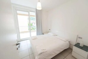 Una camera d'albergo con un letto, un comodino e una finestra con tende.