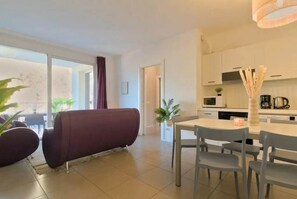 Una sala de estar moderna con un sofá, una mesa de comedor con sillas y una cocina con armarios y electrodomésticos.