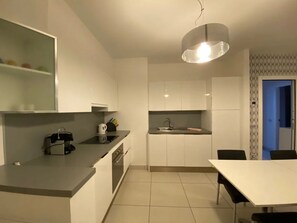 Una cocina moderna con armarios blancos, una isla central y un comedor con mesa y sillas.