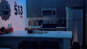 A modern kitchen with a central island, a microwave, and a refrigerator. - The 513 Flat! Pool & River View! Free Gated Parking! Walk to Banks & Stadiums! (Cincinnati)