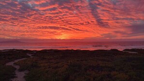 A sunset over a coastal landscape with a path leading to the beach. - Casa Azul - beachfront jacuzzi & sunsets (Ensenada)