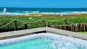 A hot tub with a clear view of the ocean and a grassy area with a rope barrier. - Casa Azul - beachfront jacuzzi & sunsets (Ensenada)
