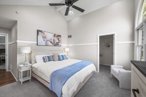 Relax in a spacious bedroom with a large bed, ceiling fan, and natural light from the window.