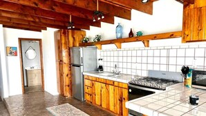 Een keuken met houten kastjes, een betegelde spatwand, een fornuis en een koelkast.