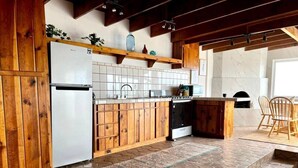 Een keuken met houten kastjes, een koelkast, een spoelbak en een fornuis.