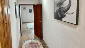 Een hal met een houten deur, een vloerkleed en een wand waarop een olifant in een lijst hangt.