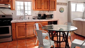 Una cocina con armarios de madera, una mesa de vidrio y sillas blancas.