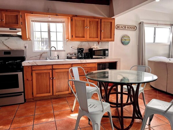 A kitchen with wooden cabinets, a glass table, and white chairs.