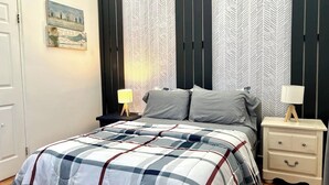 Un dormitorio con una cama, dos mesitas de noche, una lámpara y una pared con patrón de espiga.