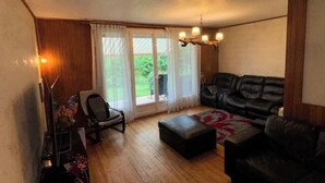 Una sala de estar con sofá, sillón, reposapiés y una araña.